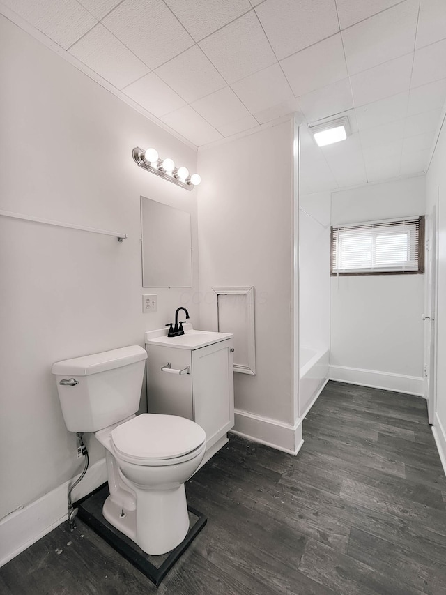 bathroom with baseboards, toilet, shower / tub combination, wood finished floors, and vanity