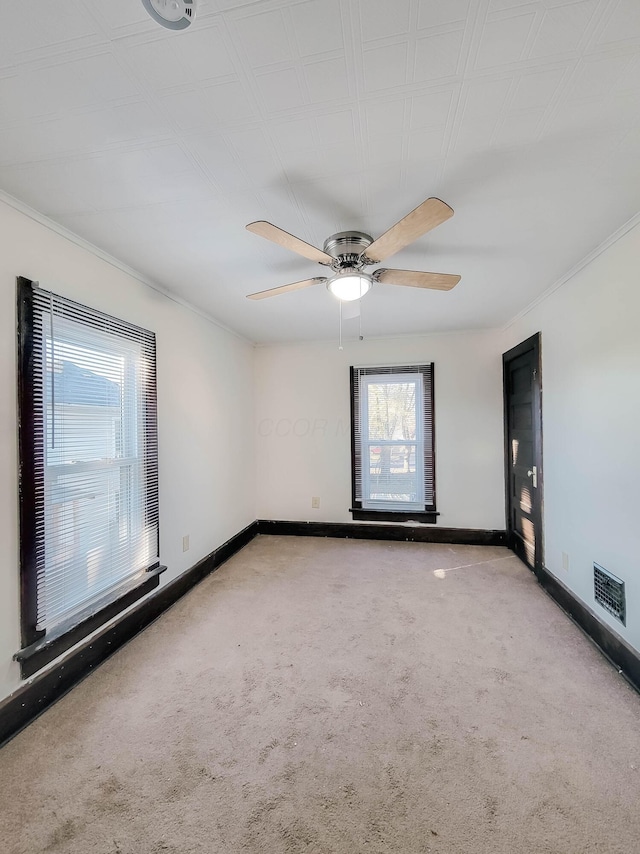 carpeted empty room with baseboards, visible vents, and ceiling fan