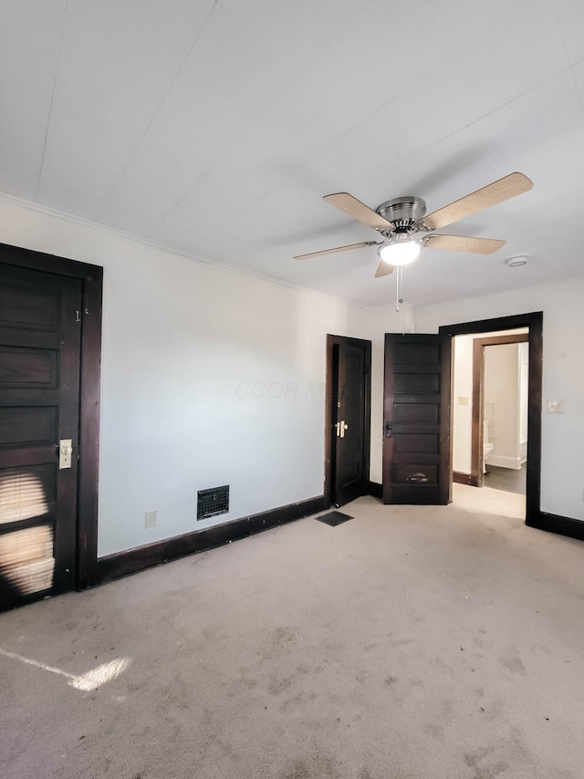 unfurnished bedroom featuring ceiling fan, carpet floors, visible vents, baseboards, and ensuite bath