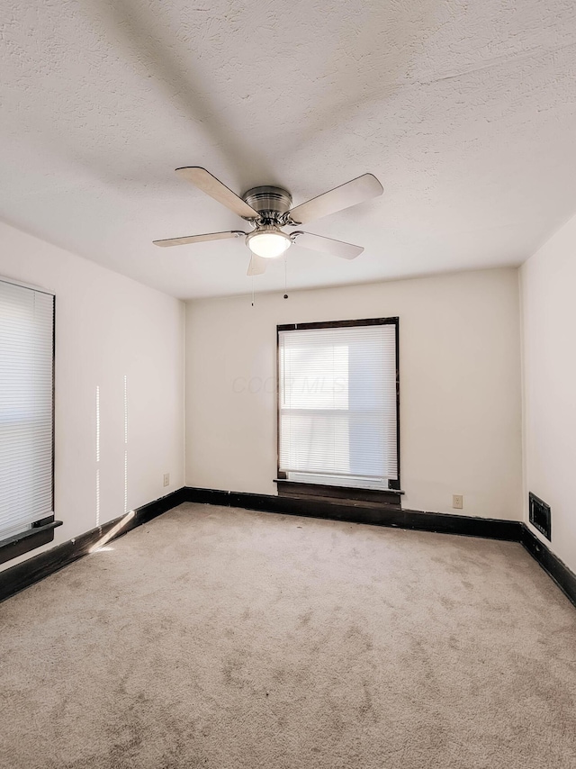 unfurnished room featuring baseboards, a textured ceiling, visible vents, and carpet flooring