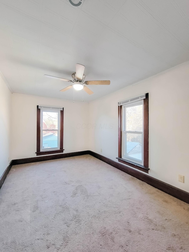 carpeted empty room featuring a ceiling fan and baseboards