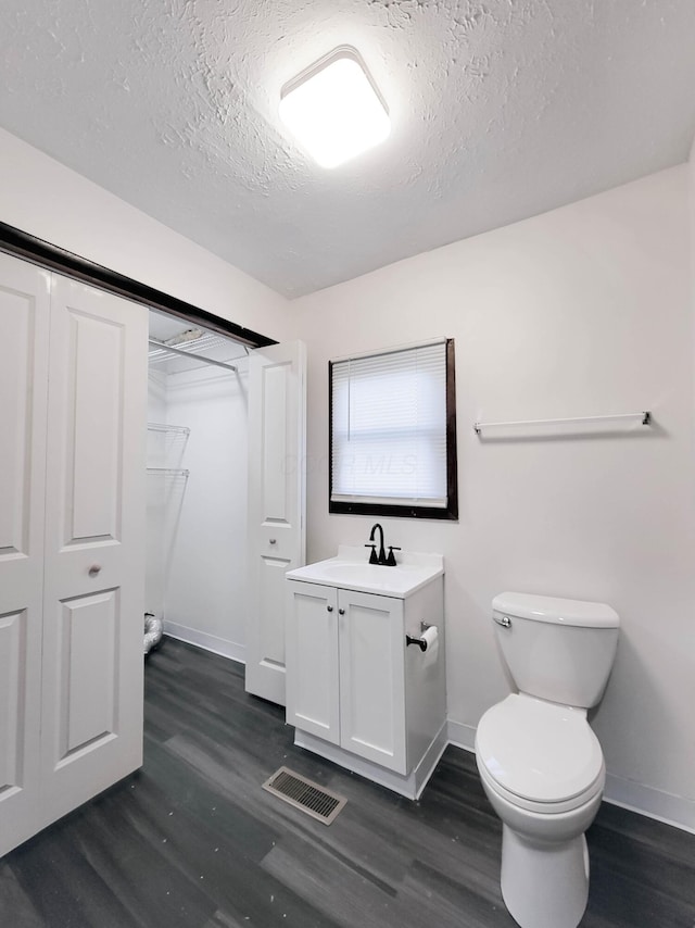 bathroom featuring visible vents, a textured ceiling, wood finished floors, and toilet