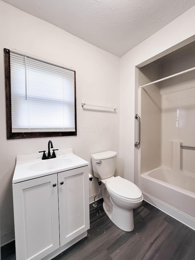 full bathroom with shower / washtub combination, toilet, a textured ceiling, vanity, and wood finished floors