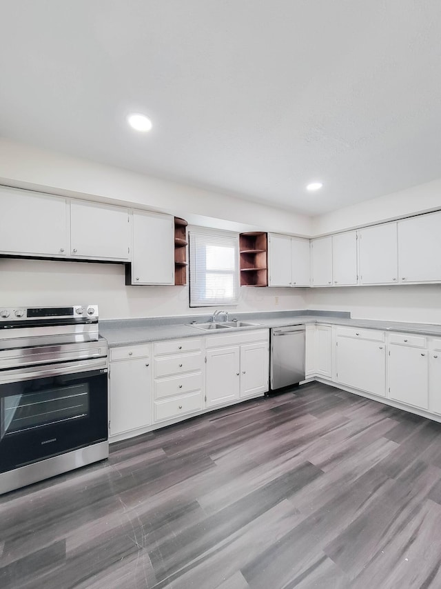 kitchen with white cabinets, wood finished floors, stainless steel appliances, open shelves, and a sink