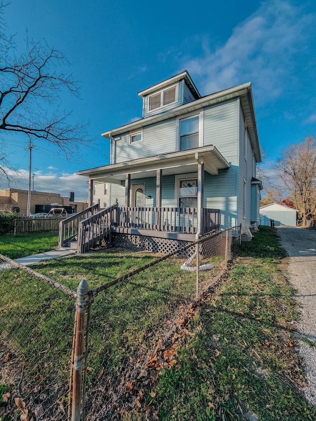 american foursquare style home featuring covered porch, a front yard, and fence