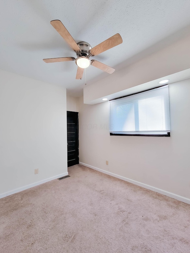 spare room with ceiling fan, carpet floors, visible vents, and baseboards