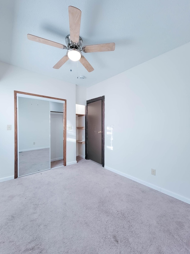 unfurnished bedroom featuring light carpet, a closet, baseboards, and a ceiling fan