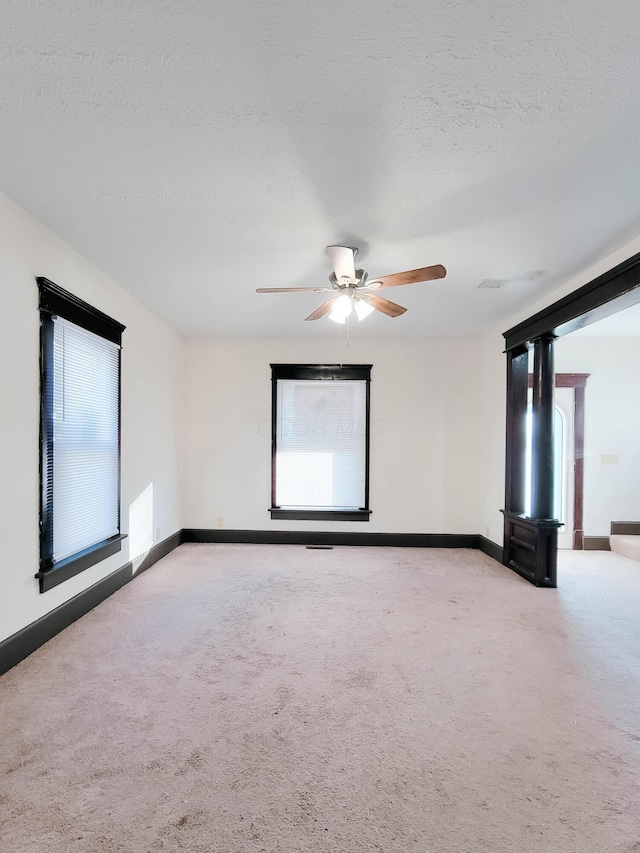 carpeted empty room with a ceiling fan, a textured ceiling, and baseboards