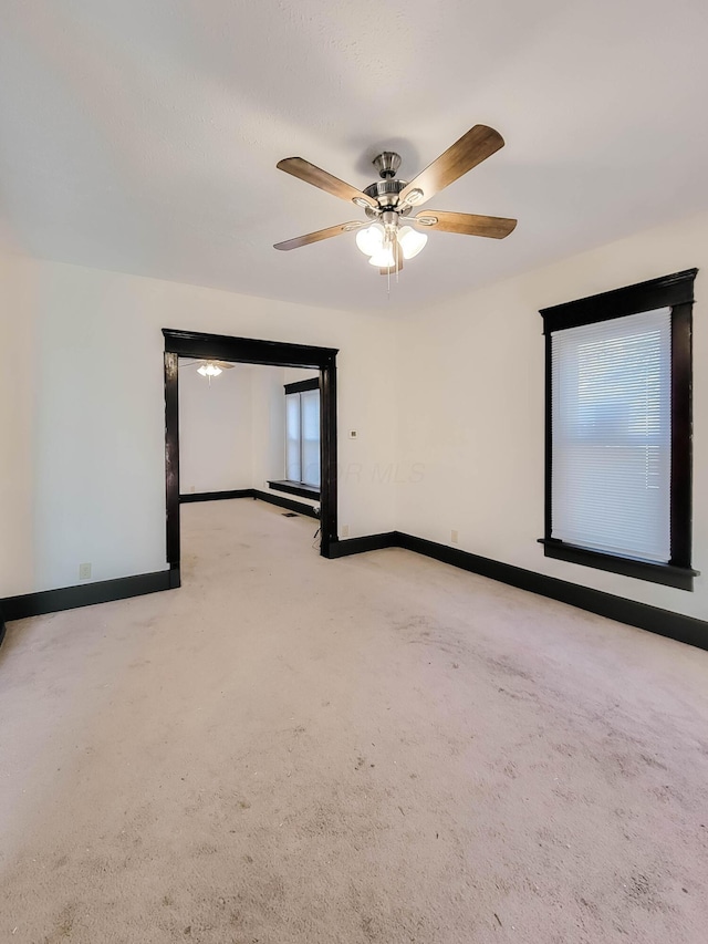 spare room with baseboards, a ceiling fan, and light colored carpet