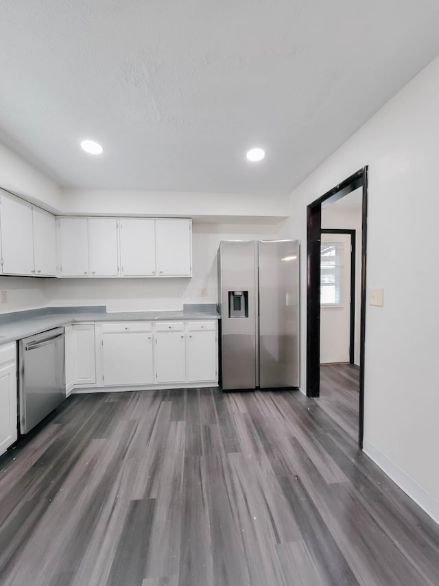 kitchen with light countertops, appliances with stainless steel finishes, dark wood-type flooring, white cabinets, and baseboards