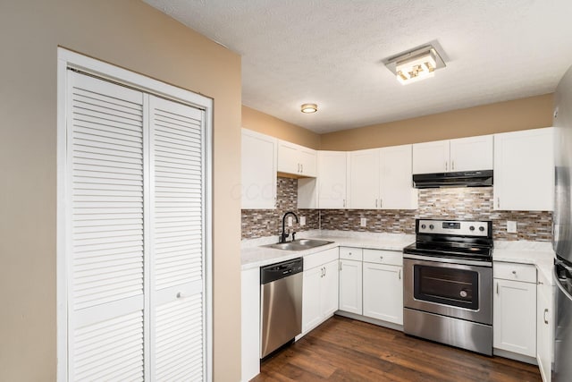 kitchen with under cabinet range hood, dark wood-style flooring, a sink, white cabinetry, and appliances with stainless steel finishes