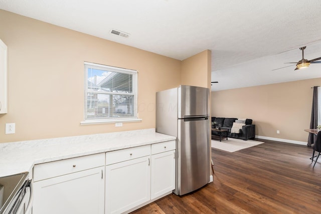 kitchen featuring visible vents, dark wood finished floors, open floor plan, freestanding refrigerator, and white cabinetry