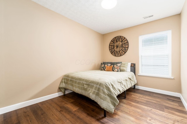 bedroom with visible vents, baseboards, and wood finished floors