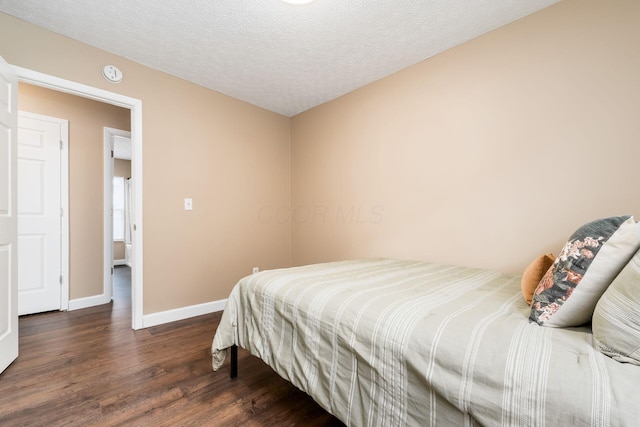 bedroom featuring a textured ceiling, baseboards, and wood finished floors