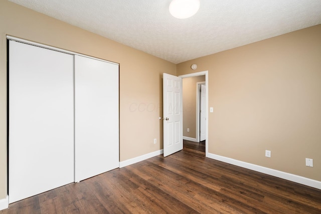 unfurnished bedroom featuring a textured ceiling, a closet, baseboards, and dark wood-style flooring