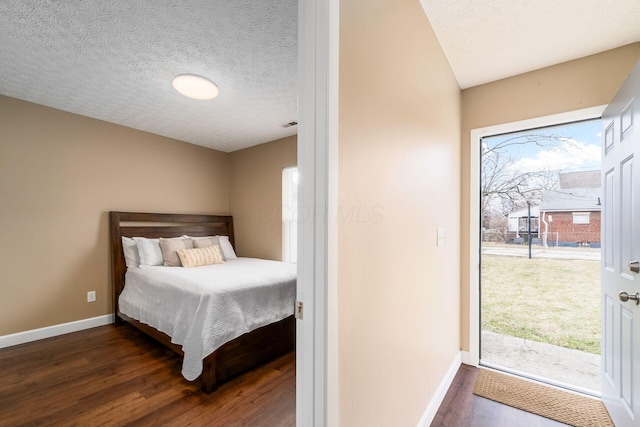 bedroom with dark wood-style floors, baseboards, and a textured ceiling