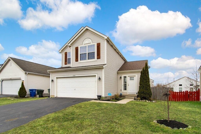 traditional home featuring a garage, driveway, a front yard, and fence