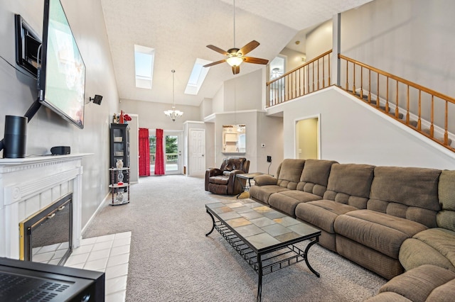 living room with ceiling fan with notable chandelier, a skylight, a fireplace, carpet flooring, and stairway