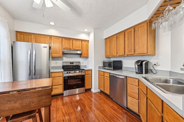 kitchen with appliances with stainless steel finishes, light countertops, dark wood finished floors, and under cabinet range hood