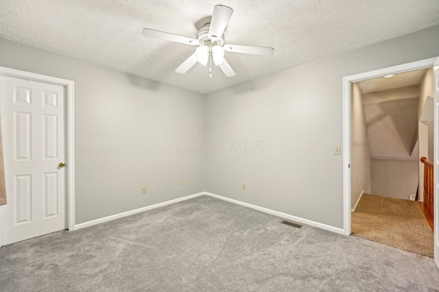 unfurnished bedroom featuring carpet floors, visible vents, ceiling fan, and a textured ceiling