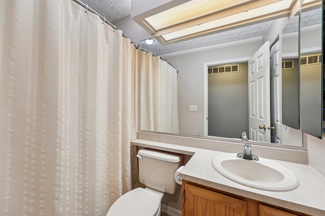 full bathroom with a skylight, visible vents, toilet, a textured ceiling, and vanity