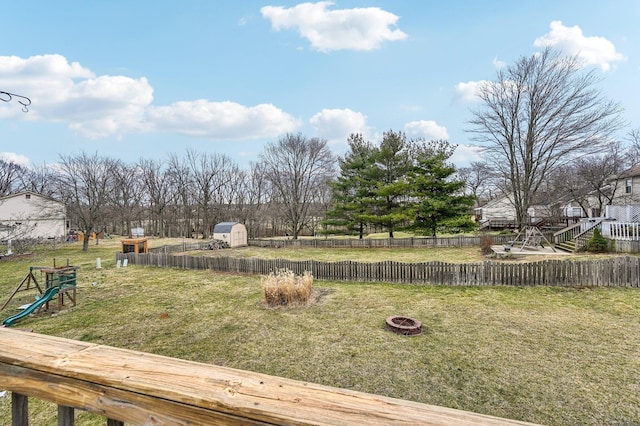 view of yard featuring an outdoor fire pit, an outdoor structure, fence, and a storage unit