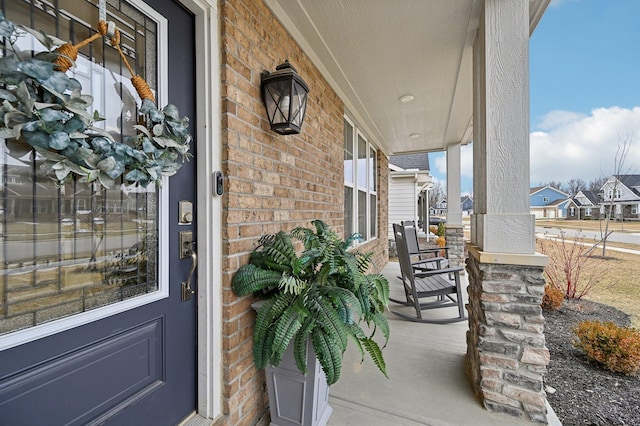 view of exterior entry with a porch and brick siding