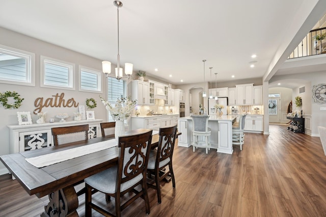 dining space with dark wood-type flooring, arched walkways, a wealth of natural light, and visible vents