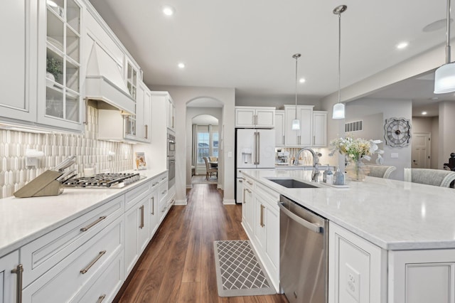 kitchen with arched walkways, stainless steel appliances, a sink, visible vents, and white cabinets