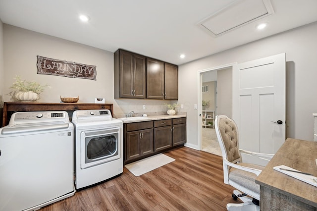 washroom featuring washer and clothes dryer, cabinet space, attic access, a sink, and wood finished floors