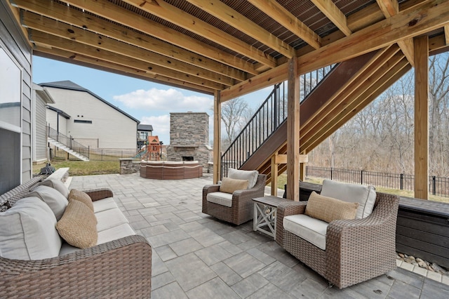 view of patio / terrace with an outdoor living space with a fireplace, fence, and stairway