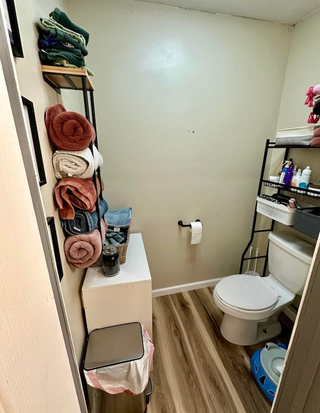 bathroom with baseboards, toilet, and wood finished floors