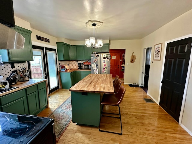 kitchen with green cabinets, wooden counters, appliances with stainless steel finishes, and visible vents