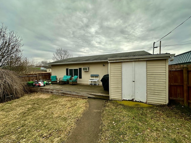 rear view of property with an outdoor structure, fence, a deck, and a yard