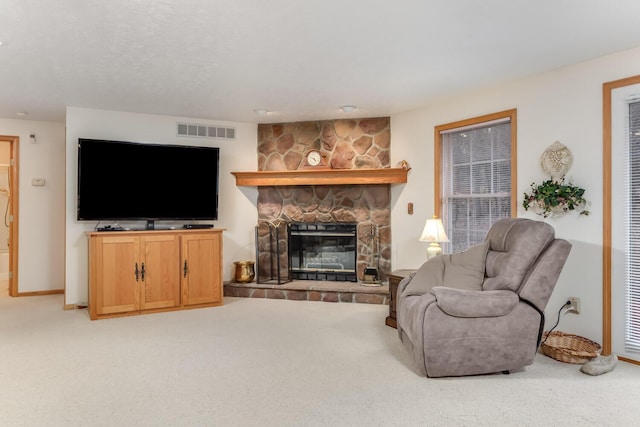 living room featuring carpet floors, a stone fireplace, and visible vents