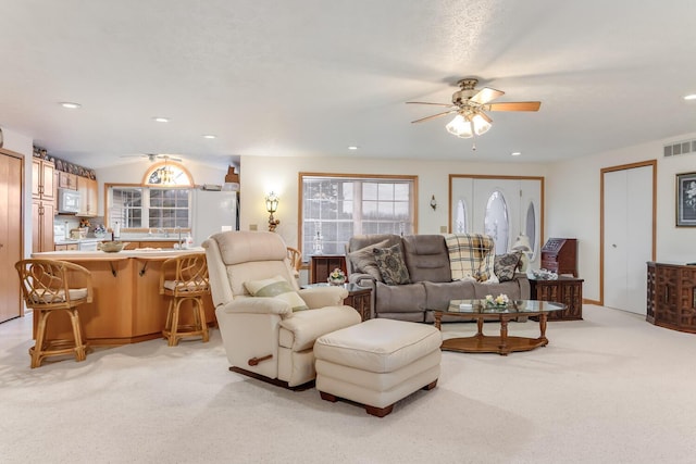 living room with light carpet, visible vents, a ceiling fan, and recessed lighting