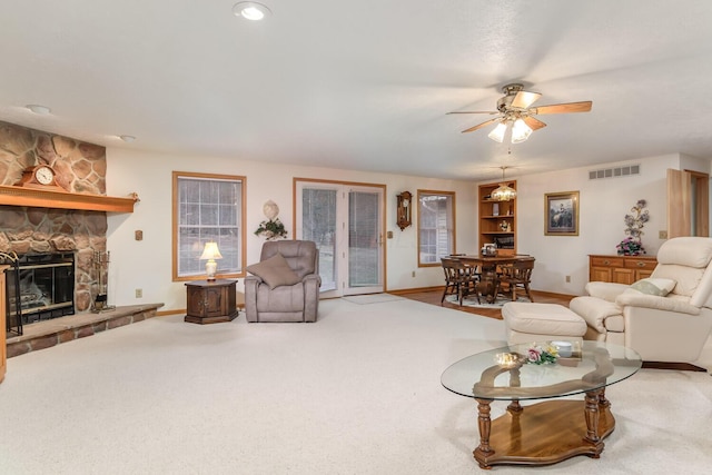 living room featuring baseboards, visible vents, a ceiling fan, carpet floors, and a fireplace