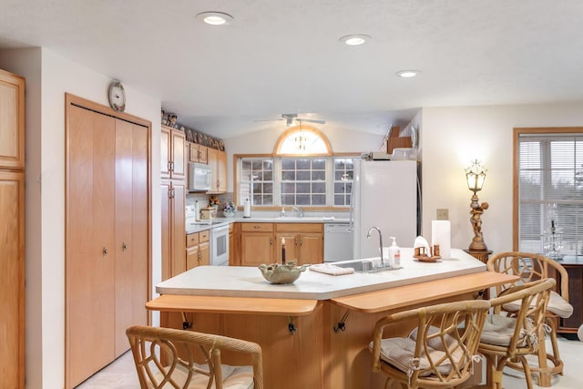 kitchen with recessed lighting, white appliances, a breakfast bar, a sink, and light countertops