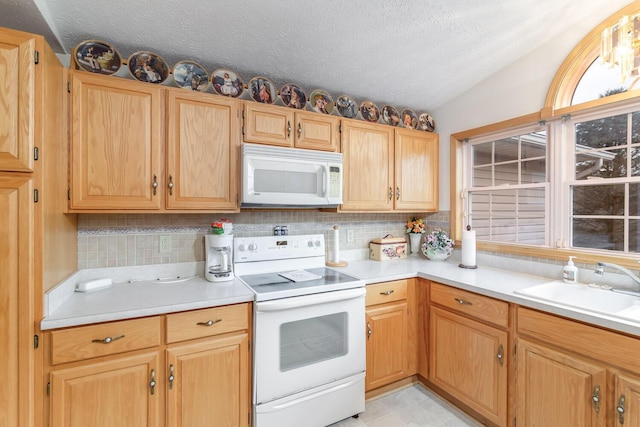 kitchen with white appliances, vaulted ceiling, light countertops, and a sink