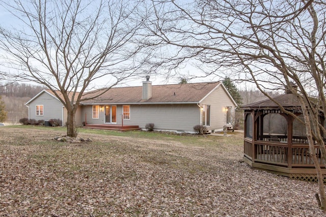 back of property with a shingled roof, a chimney, a deck, and a gazebo