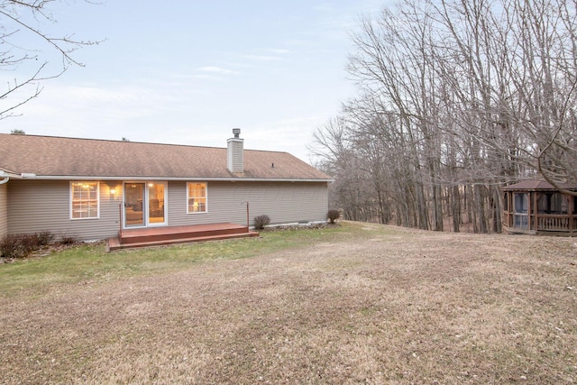 rear view of property with a yard, a chimney, a shingled roof, a gazebo, and a wooden deck