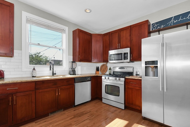 kitchen with light stone counters, visible vents, light wood-style flooring, appliances with stainless steel finishes, and a sink