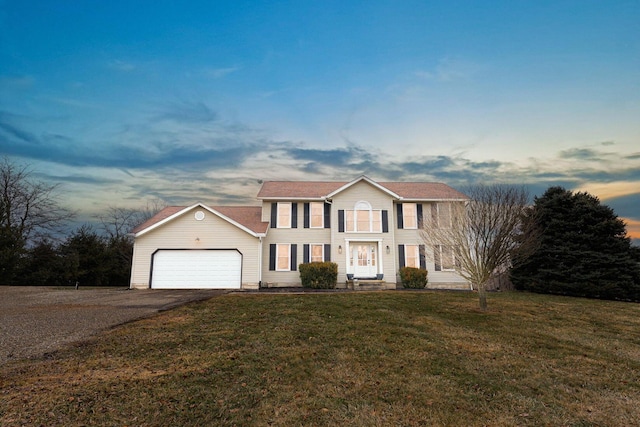 colonial inspired home featuring an attached garage, a front lawn, and aphalt driveway