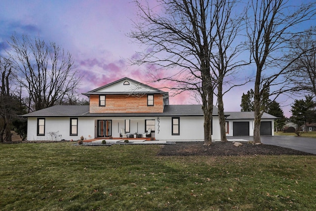 view of front facade with a porch, a front lawn, driveway, and an attached garage