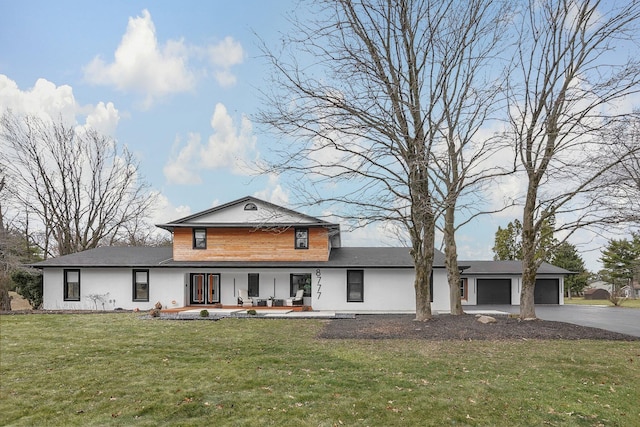 view of front of home featuring a garage, a front yard, covered porch, and aphalt driveway