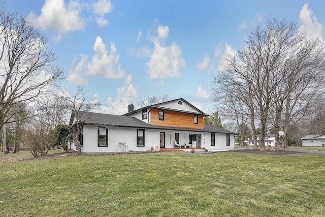 back of house featuring a chimney and a lawn