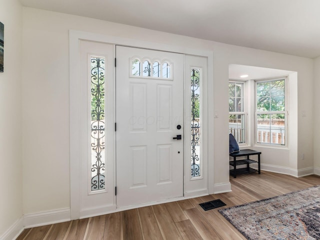 foyer featuring baseboards, visible vents, and wood finished floors