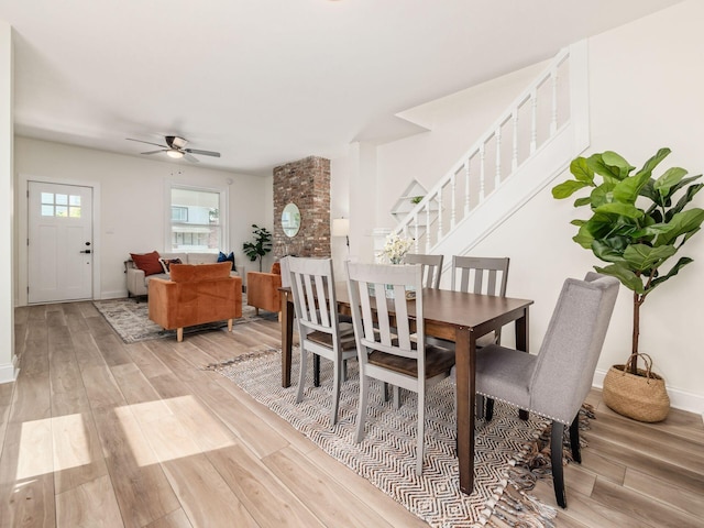 dining space with a ceiling fan, light wood-type flooring, stairway, and baseboards