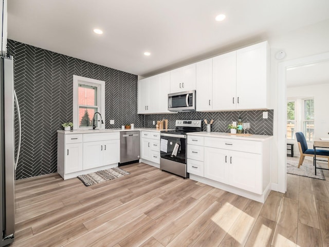 kitchen with stainless steel appliances, a sink, light countertops, and white cabinets