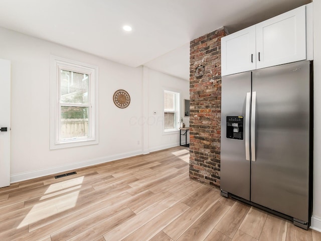 kitchen with a healthy amount of sunlight, light wood-type flooring, stainless steel fridge, and visible vents